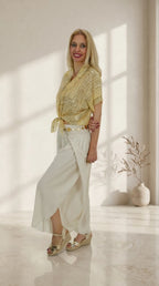 Look Pantalón Bali con camisa de estampado bandana amarilla y cinturón de flores dorado.