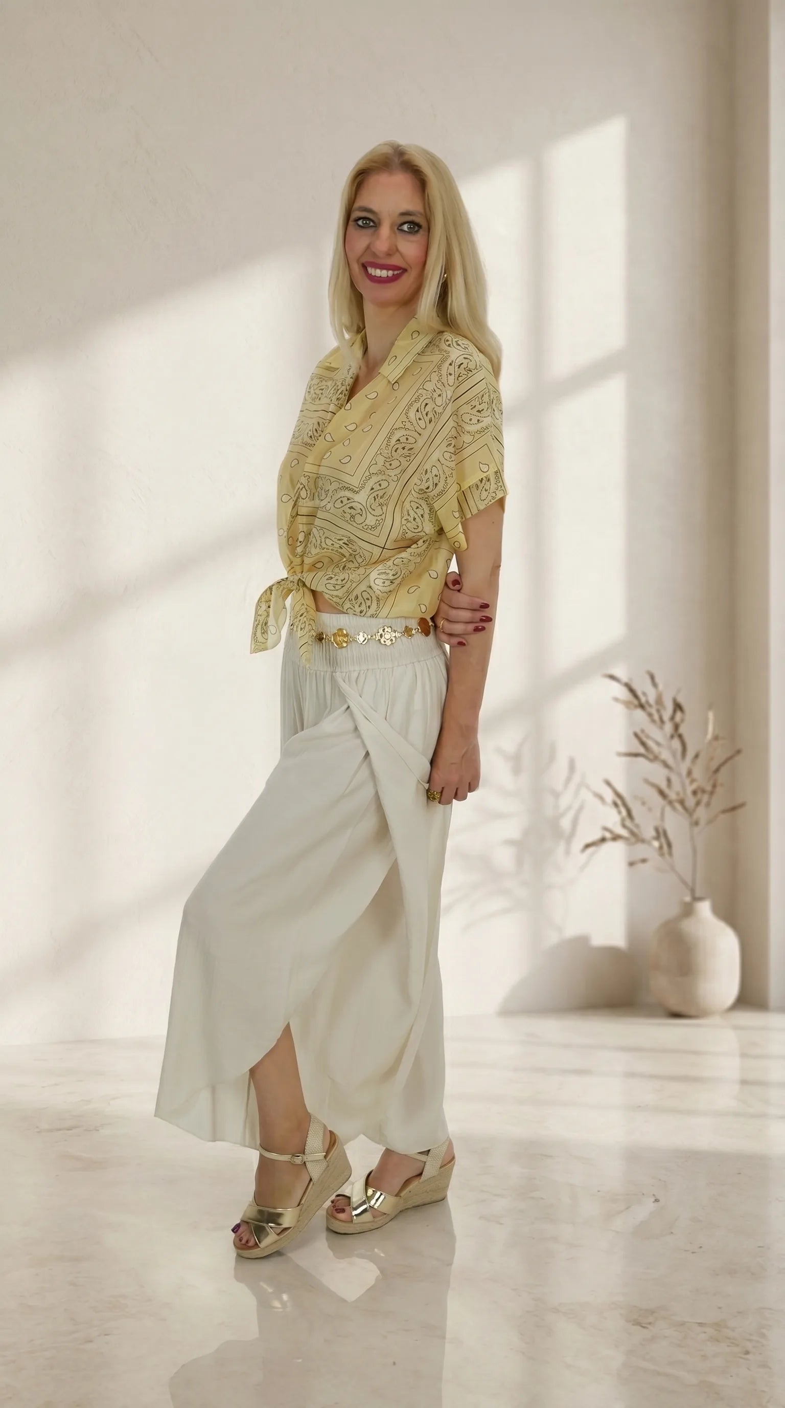 Look Pantalón Bali con camisa de estampado bandana amarilla y cinturón de flores dorado.
