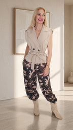 Modelo con chaleco cruzado beige, cinturón anudado y pantalón globo de camuflaje con bajos fruncidos.