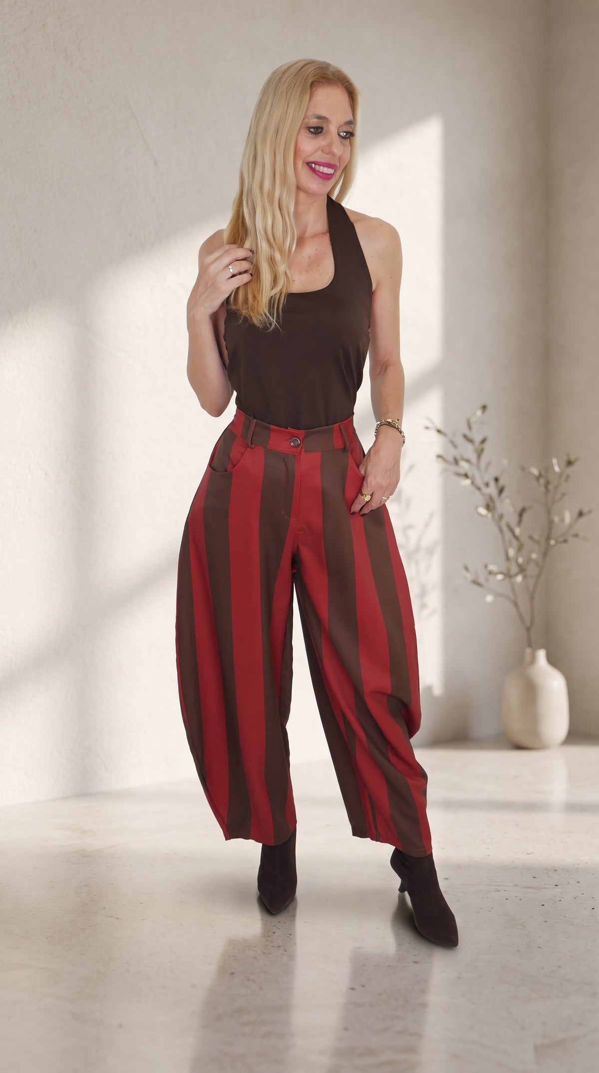 Modelo con pantalón barrel de rayas anchas en caldera y marrón, combinado con un top marrón sin mangas.