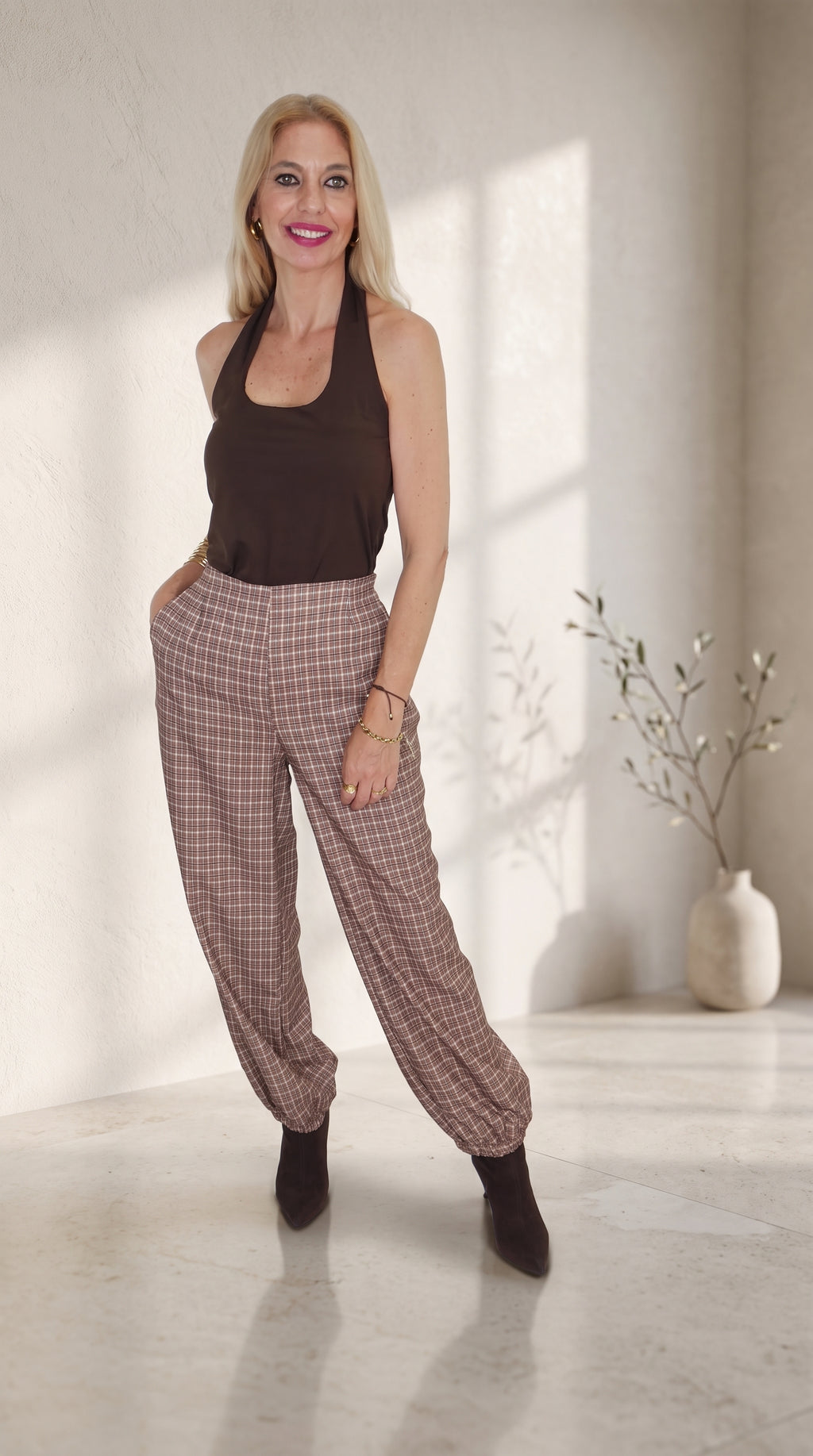 Modelo con pantalón balloon de cuadros marrones y bajos fruncidos, combinado con un top marrón sin mangas.