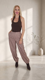 Modelo con pantalón balloon de cuadros marrones y bajos fruncidos, combinado con un top marrón sin mangas.
