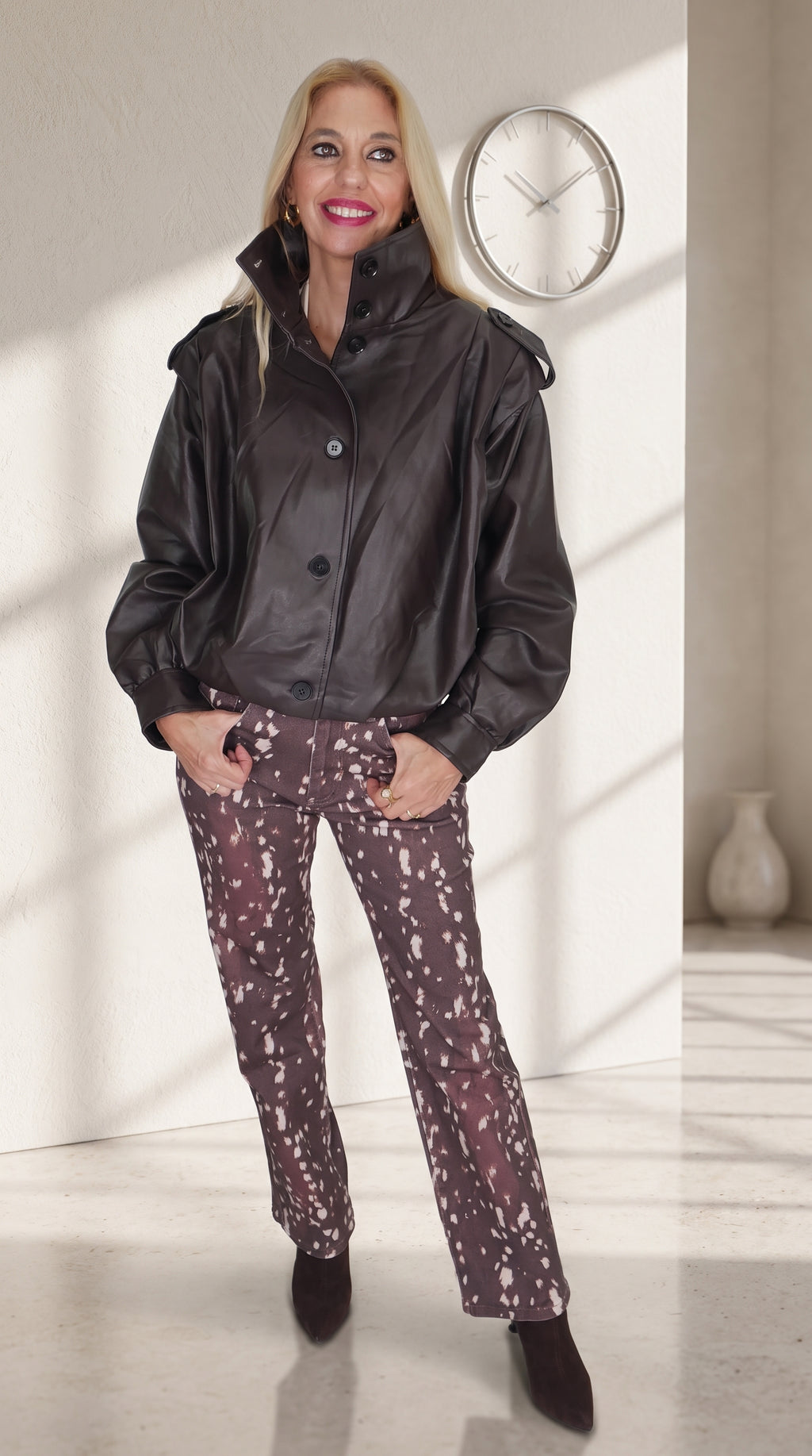 Modelo con chaqueta marrón efecto piel de bajo fruncido y jeans Bambi de estampado moteado.