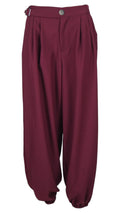 Pantalón Hebilla en color burdeos, con pinzas delanteras, pequeña hebilla lateral y bajos elásticos.