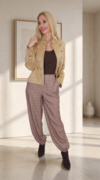 Modelo con chaqueta militar camel abierta, botones decorativos y manga larga, combinada con pantalón de cuadros.