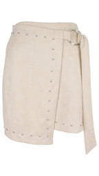 Minifalda efecto ante en color beige, con diseño cruzado, tachas y lazada lateral con aro metálico.