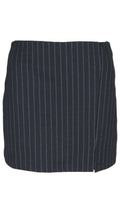 Falda pantalón sastre en color negro, con rayas diplomáticas, corte mini y pequeña abertura en el bajo.