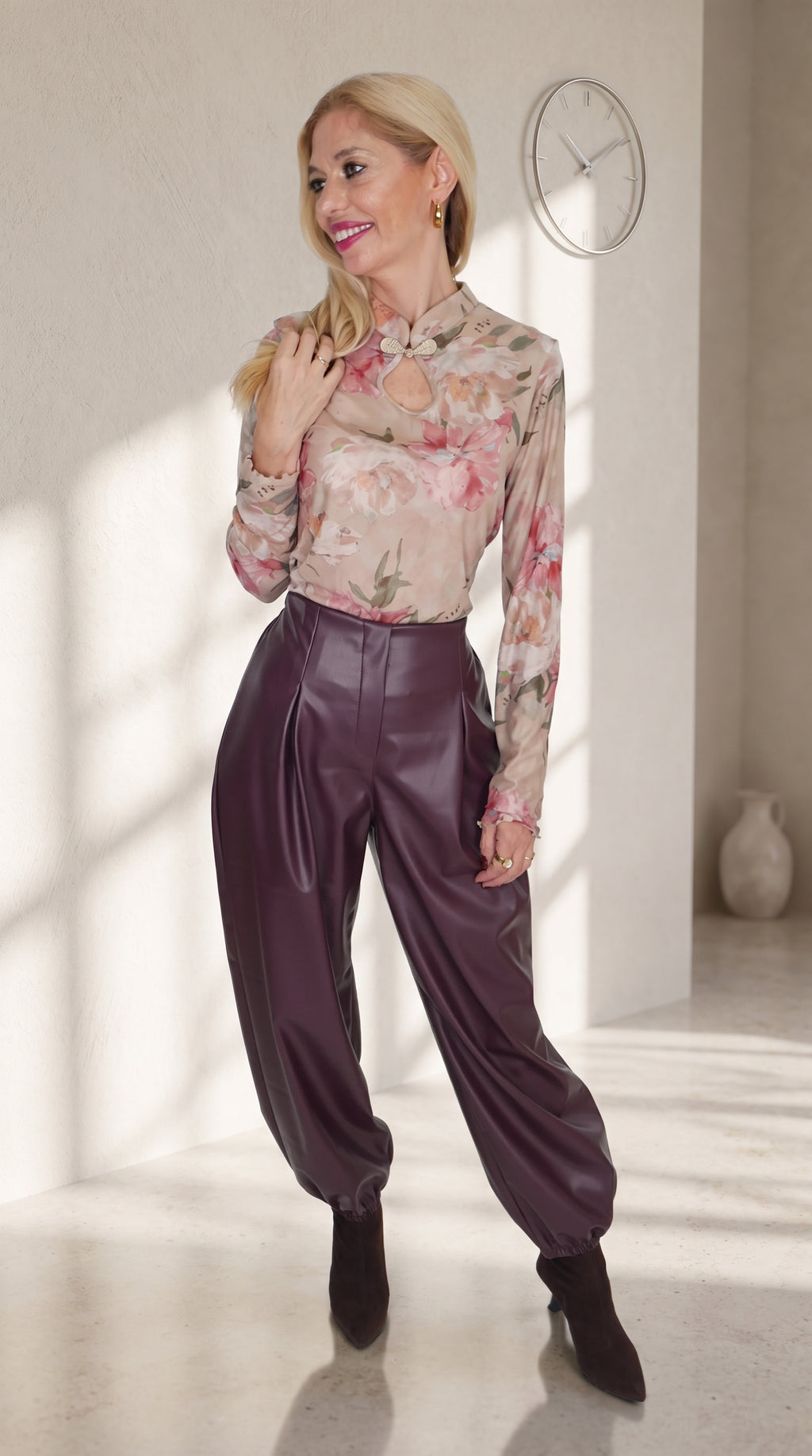 Modelo con pantalón globo morado efecto piel y bajos fruncidos, combinado con un top floral de manga larga.