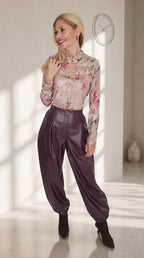 Modelo con pantalón globo morado efecto piel y bajos fruncidos, combinado con un top floral de manga larga.