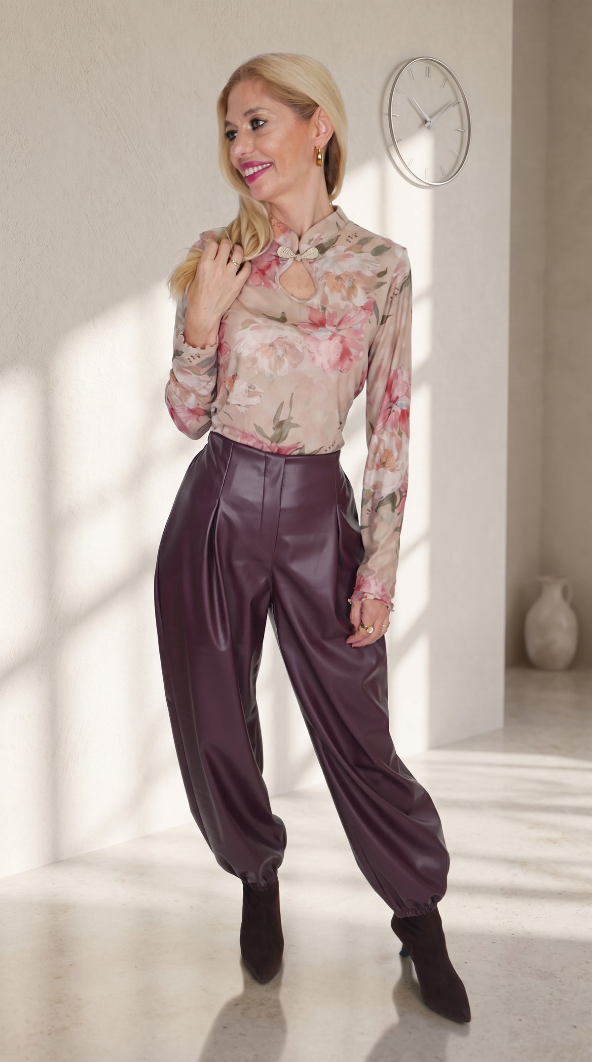 Modelo con pantalón globo morado efecto piel y bajos fruncidos, combinado con un top floral de manga larga.