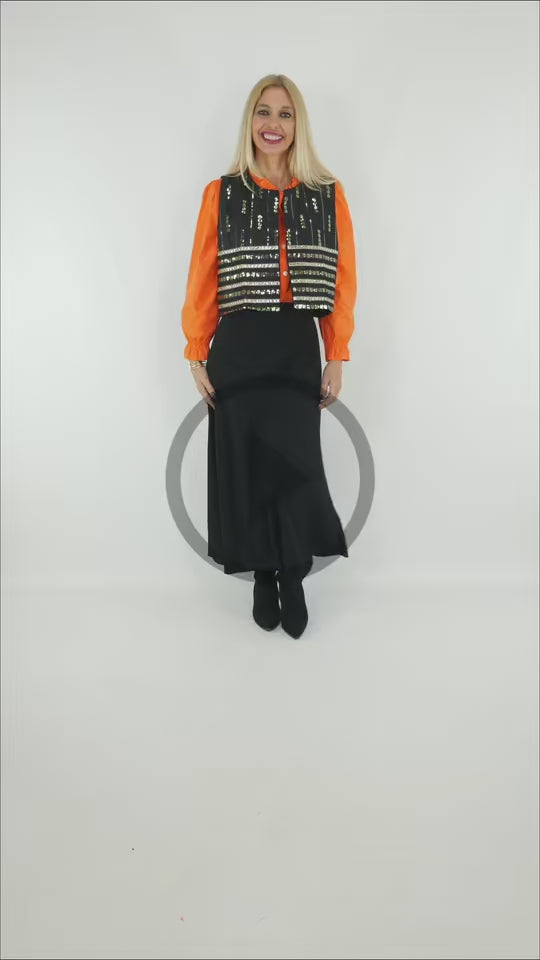 Video del Look Chaleco Lentejuelas con falda larga negra y camisa naranja